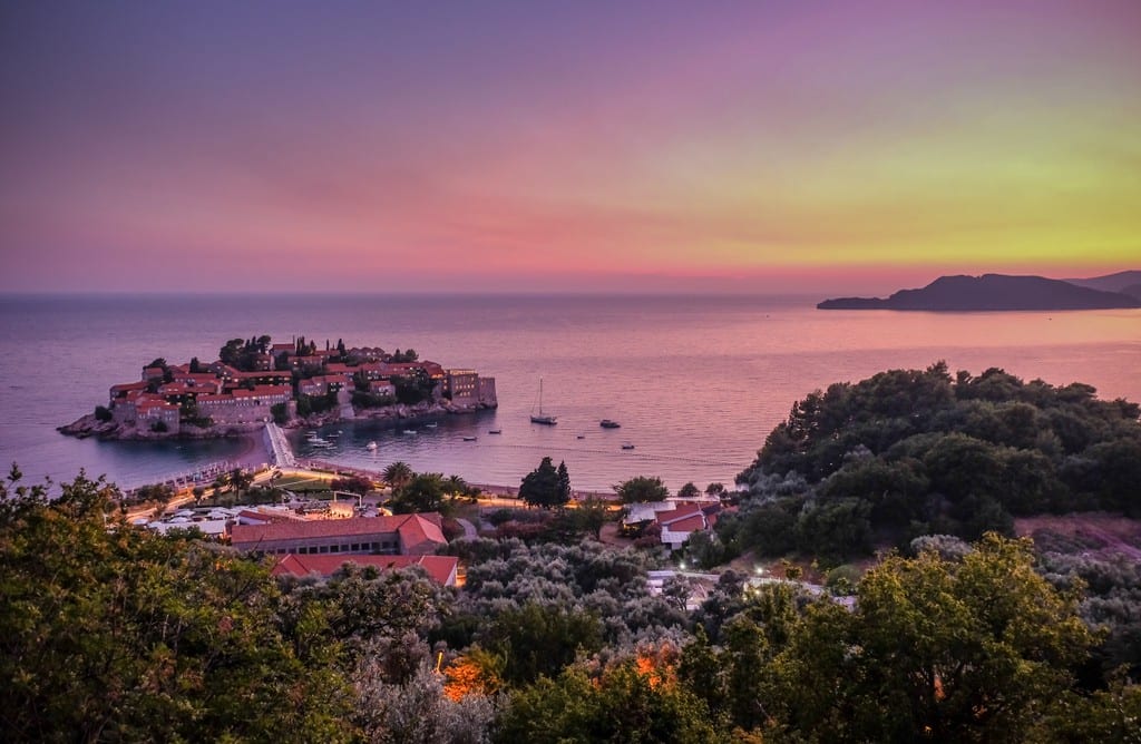 A bright pink and yellow sunset over the island of Sveti Stefan, just off the coast of Montenegro.