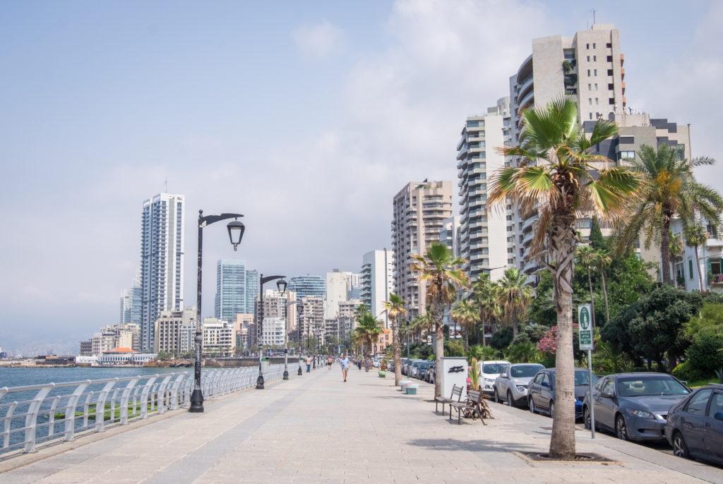 The corniche in Beirut: a wide cement pathway along the sea. In the background are tall high-rises and palm trees.