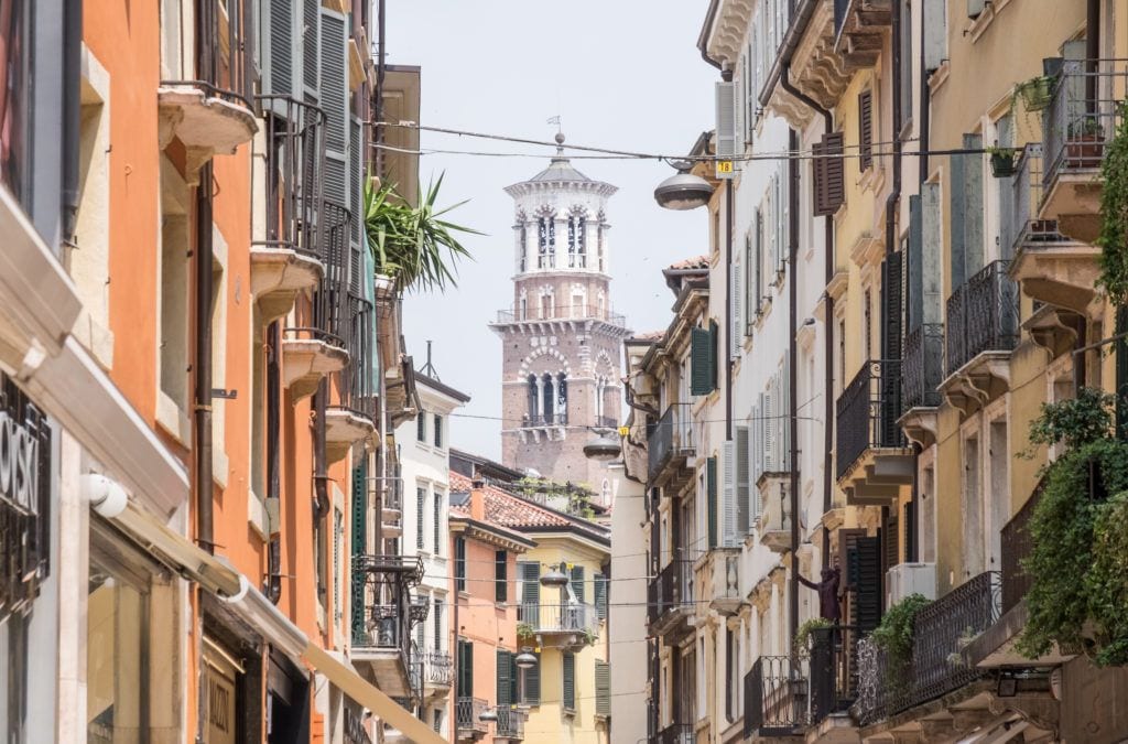 In Verona, you see the tower of a church rising in between residential buildings painted gold and yellow.