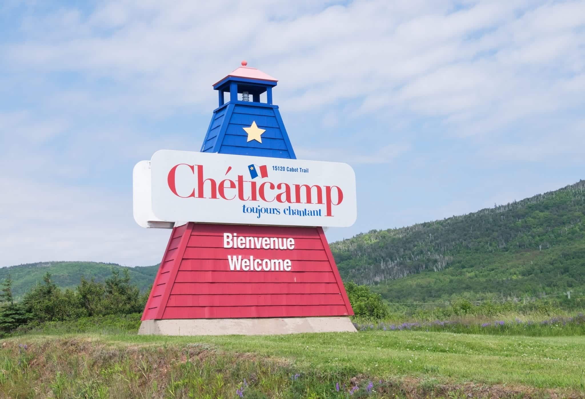 A red and blue Cheticamp sign shaped like a lighthouse.