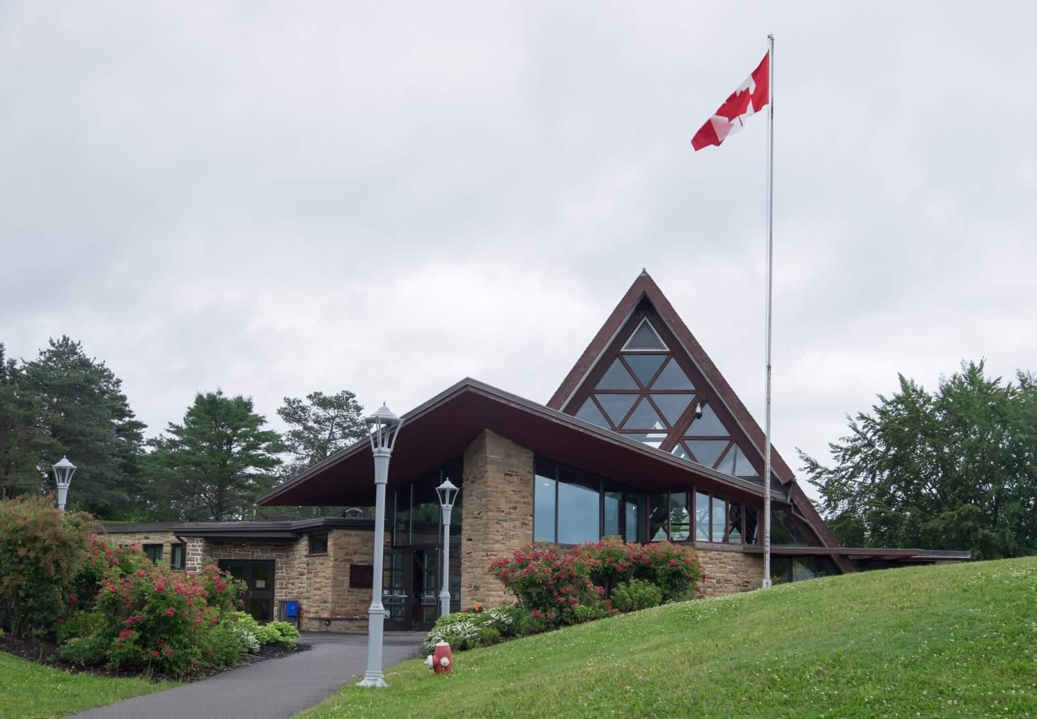 A modern triangular church-shaped building with a Canadian flag flying in front.