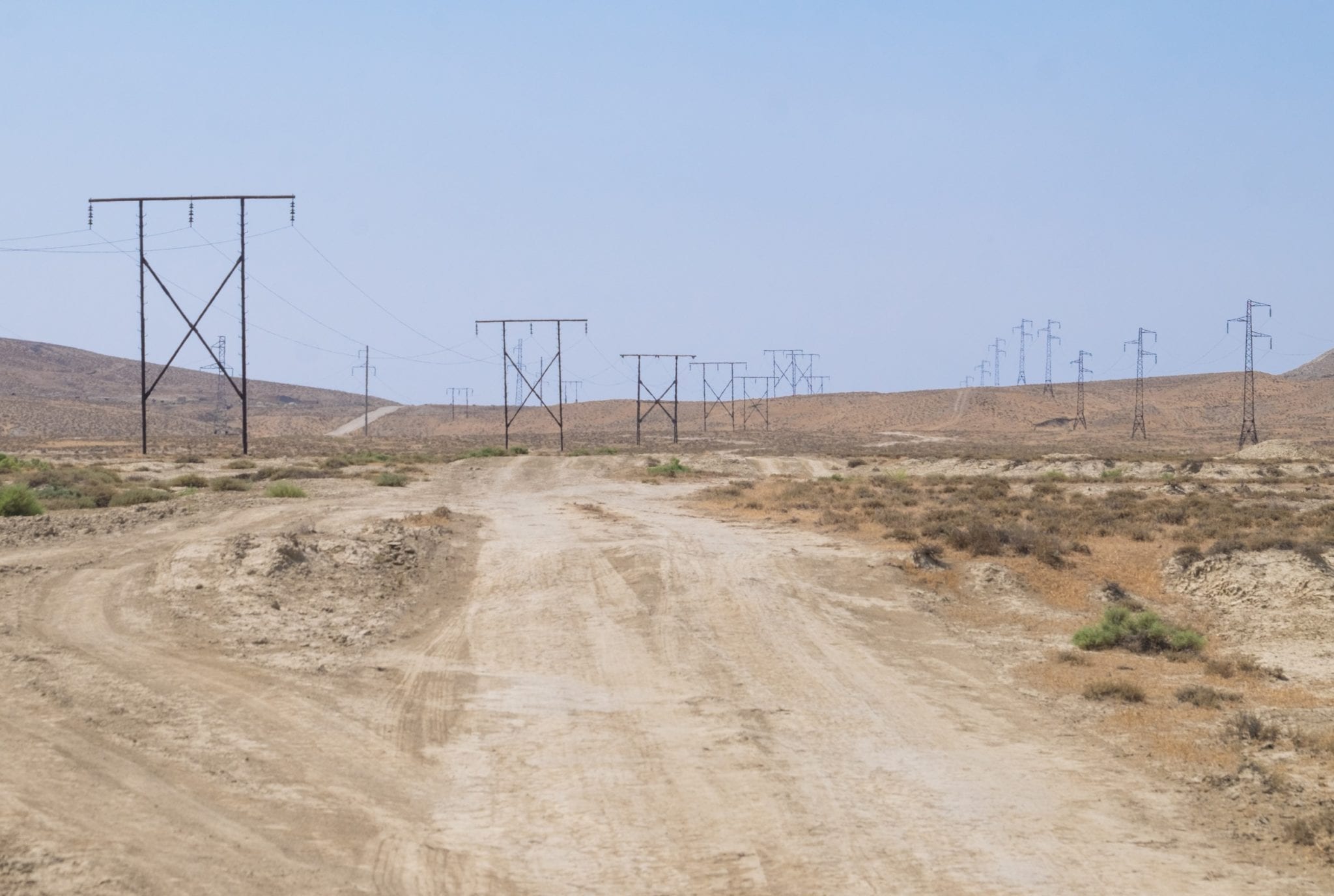 A rough desert landscape with telephone poles running across the sand.