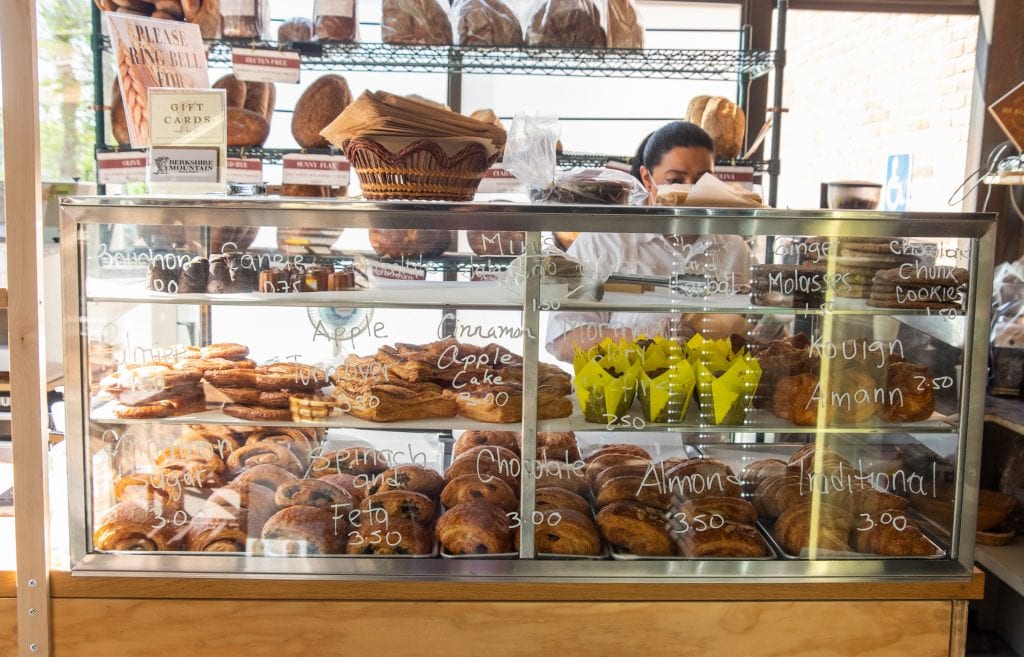 A clear glass pastry case filled with croissants, turnovers, and other baked goodies.