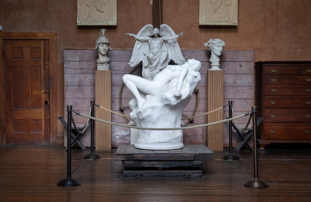 A marble statue of a naked woman leaning back, arching her back, an angel above her.