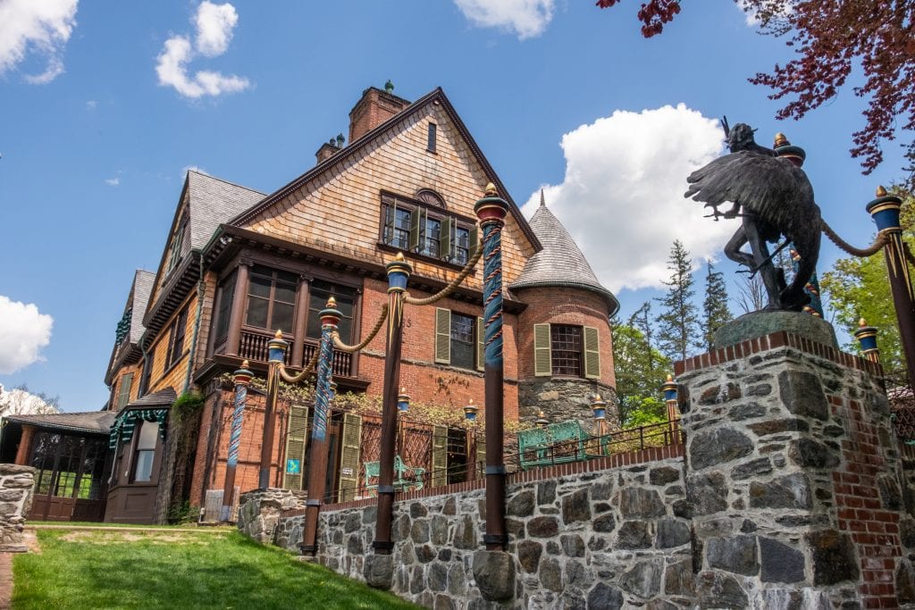 A brick mansion with an immaculate stone wall in front of it.