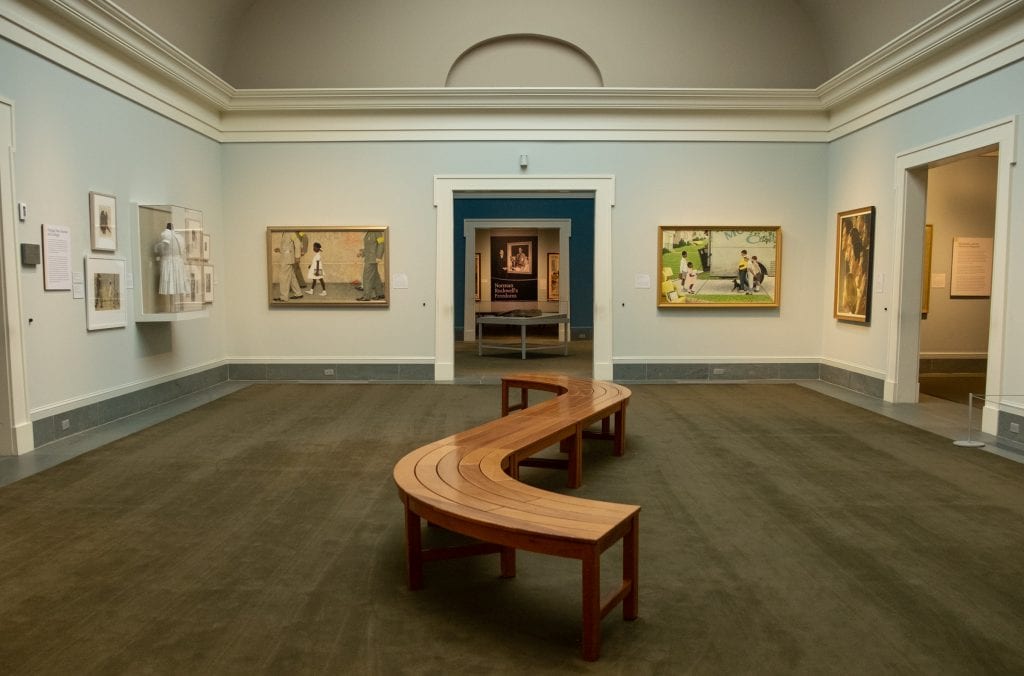 Interior of the Norman Rockwell Museum, paintings on walls. You see his famous painting of Ruby Bridges walking to school on the left.