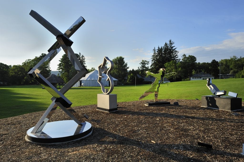 Several metallic sculptures posed on a green lawn.