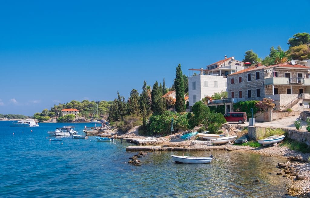 A small coastal Croatian village on the island of Vis, a few kayaks in the calm water, white stone houses on shore.