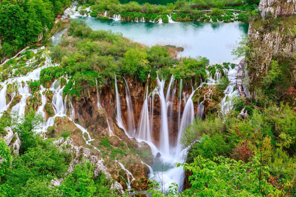 A series of skinny cascading waterfalls falling from one lake into another at Plitvice.