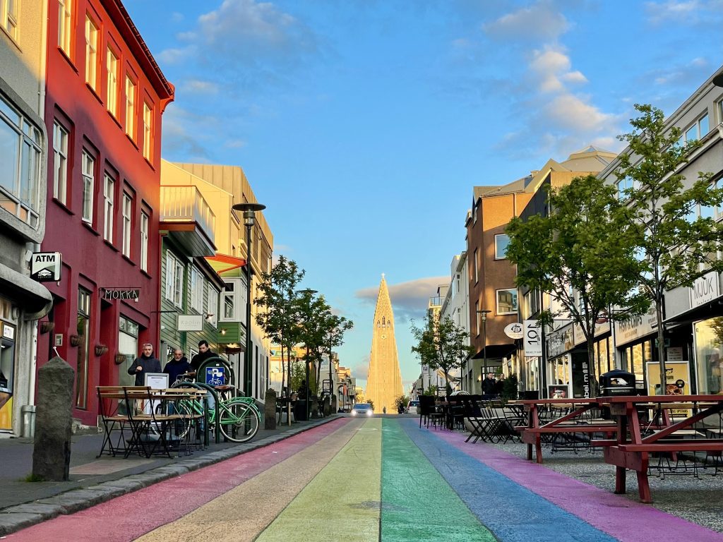 A street painted in rainbow stripes leading up to the pointy gray church.