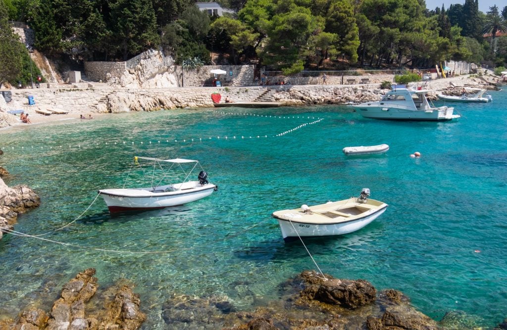 Two small white wooden boats in a bright teal cove in Hvar, Croatia.