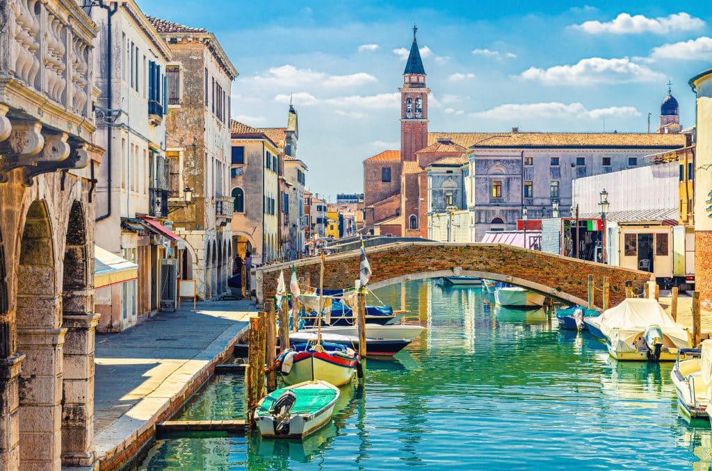 An Italian town with canals, bridges, and a tall church tower, that looks a lot like Venice.